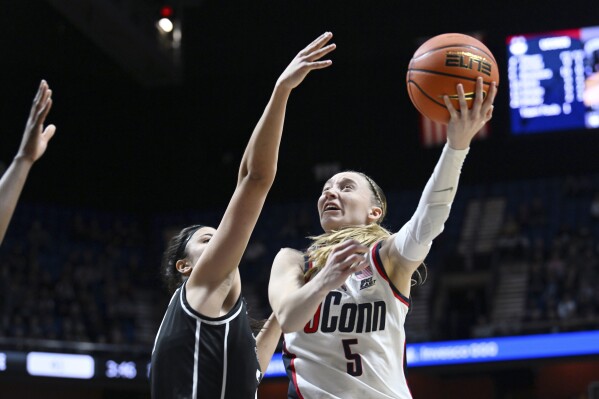 UConn guard Paige Bueckers (5) shoots over Providence Friars forward Olivia Olsen (31) during an NCAA college basketball game in the quarterfinals of the a Big East tournament, Saturday, March 9, 2024, at the Mohegan Sun Arena in Uncasville, Conn. (Cloe Poisson/Hartford Courant via AP)