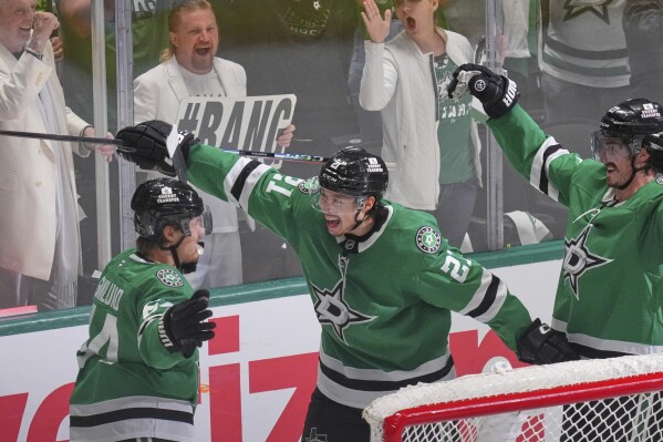 Dallas Stars center Mikael Granlund (64) celebrates a goal with teammates Jason Robertson (21) and Mason Marchment during the third period in Game 1 of the Western Conference finals in the NHL hockey Stanley Cup playoffs against the Edmonton Oilers, Wednesday, May 21, 2025, in Dallas. (AP Photo/LM Otero)