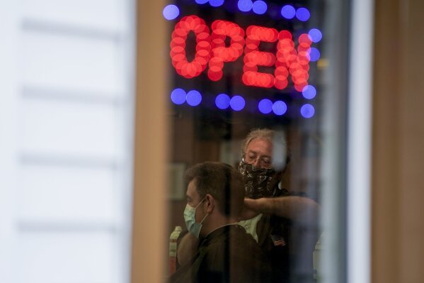 Owner Paul Furrer cuts the hair of Jeff Jones at Rich's Barber Shop on Thursday, May 14, 2020, in Waukesha, Wis. The store re-opened after the Wisconsin Supreme Court struck down Gov. Tony Evers' stay-at-home order Wednesday. (AP Photo/Morry Gash)