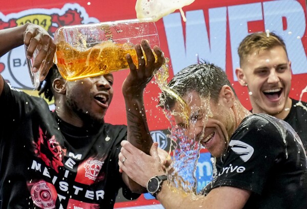 Leverkusen's head coach Xabi Alonso , centre, is sprayed with beer after Bayer Leverkusen won the German Bundesliga title beating Werder Bremen in Leverkusen, Germany, Sunday, April 14, 2024. (AP Photo/Martin Meissner)