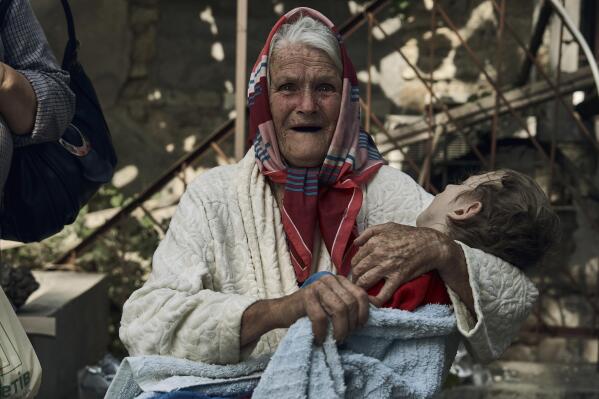 An elderly woman holds a disabled relative as they are evacuated from a flooded neighbourhood in Kherson, Ukraine, Thursday, June 8, 2023. Floodwaters from a collapsed dam kept rising in southern Ukraine on Thursday, forcing hundreds of people to flee their homes in a major emergency operation that brought a dramatic new dimension to the war with Russia, now in its 16th month. (AP Photo/Libkos)