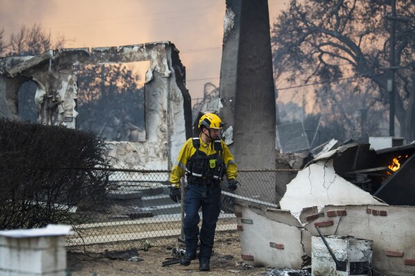 A firefighter walks around a burned structure while battling the Eaton Fire, Wednesday, Jan. 8, 2025, in Altadena, Calif. (AP Photo/Nic Coury)