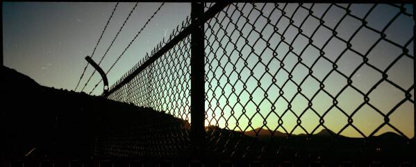 The sun sets over the fence of the Lavender Pit Mining Overlook in Bisbee, Ariz., Oct. 26, 2021. The year 1995, when The Church of Jesus Christ of Latter-day Saints established the “help line,” was a pivotal time for the church and other organized religions. Child sex abuse lawsuits were on the rise and juries were awarding victims millions of dollars. Perhaps more ominous for religious institutions, insurance companies were canceling their coverage of child sex abuse claims. (AP Photo/Dario Lopez-Mills)