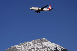 An Austrian Airlines plane flies low over the Alps on approach to Innsbruck airport, Austria, Monday, Jan. 2, 2023. (AP Photo/Matthias Schrader)