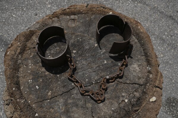 Rusty shackles rest on a tree stump as part of a Good Friday observance symbolizing Christ's suffering and sacrifice in Quraye, near the southern port city of Sidon, Lebanon, Friday, April 18, 2025. (AP Photo/Hassan Ammar)