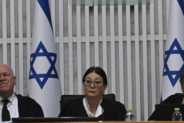 Esther Hayut, chief justice of the Supreme Court of Israel, center, sits on the bench with justices Uzi Vogelman, left, and Issac Amit, right, during a session with all of Israel's Supreme Court justices for the first time in the country's history to look at the legality of Prime Minister Benjamin Netanyahu's contentious judicial overhaul, which the government pushed through parliament in July, in Jerusalem, Tuesday, Sept. 12, 2023. The divisive law, which cancels the court's ability to block government actions and appointments using the legal concept that they are "unreasonable," is the first piece of the wider government plan to weaken the Supreme Court. (Debbie Hill/Pool Photo via AP)
