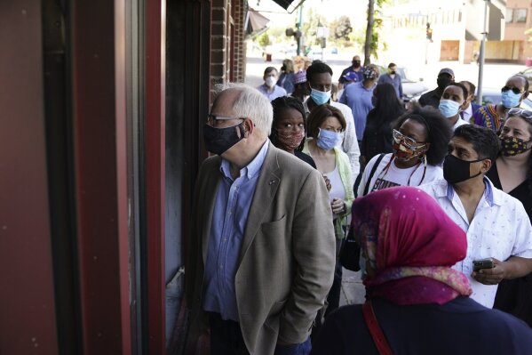 Minnesota Gov. Tim Walz walks with business owners that were affected by events following the George Floyd protests Friday, June 5, 2020 at Hawthorne Crossings in north Minneapolis. Floyd died after being restrained by Minneapolis police officers on May 25. (Anthony Souffle/Star Tribune via AP)
