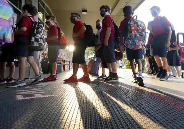 FILE - In this Aug. 17, 2021, file photo, wearing masks to prevent the spread of COVID-19, elementary school students line up to enter school for the first day of classes in Richardson, Texas. As COVID-19 cases surge, a majority of Americans say they support mask mandates for students and teachers in K-12 schools, but their views are sharply divided along political lines. (AP Photo/LM Otero, File)