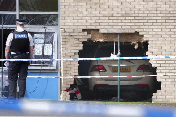 Police officers stand beside the debris and damage to the Beacon Church of England Primary School after a car crashed into the building in Anfield, Liverpool, England, Monday, April 22, 2024. A driver who plowed through the wall of a classroom shortly before the start of school has been arrested on suspicion of using drugs. (Peter Byrne/PA via AP)