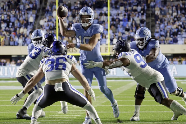 North Carolina quarterback Drake Maye (10) gets the pass off to complete a 2-point conversion, past Duke linebacker Nick Morris Jr. (36) and defensive tackle DeWayne Carter (90) during the second overtime of an NCAA college football game Saturday, Nov. 11, 2023, in Chapel Hill, N.C. (AP Photo/Chris Seward)