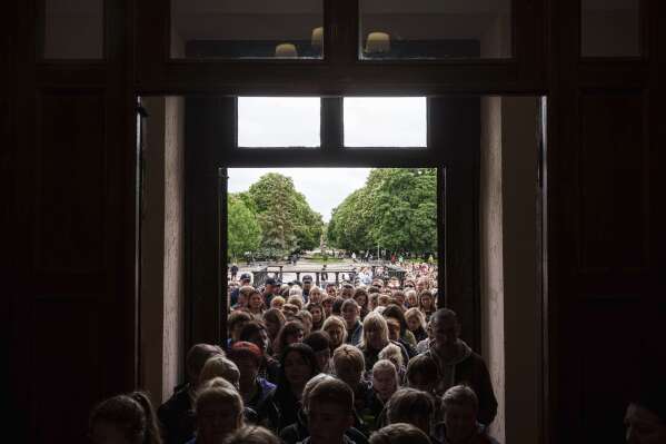 Local residents line up to enter a funeral ceremony for Tamara Martyniuk, 8, Stanislav Martyniuk, 12, and Roman Martyniuk, 17, killed in a Russian strike on Sunday, in Korostyshiv, Zhytomyr region, Ukraine, Wednesday, May 28, 2025. (AP Photo/Evgeniy Maloletka)