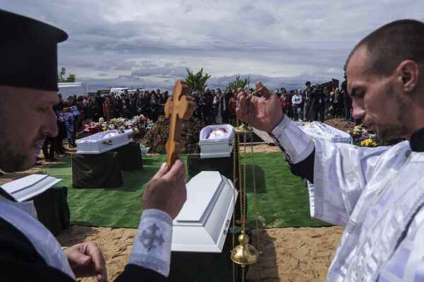 Priests conduct a memorial service for Roman Martyniuk, 17, Tamara Martyniuk, 8, and Stanislav Martyniuk, 12, killed in a Russian strike on Sunday, during farewell ceremony in Korostyshiv, Zhytomyr region, Ukraine, Wednesday, May 28, 2025. (AP Photo/Evgeniy Maloletka)