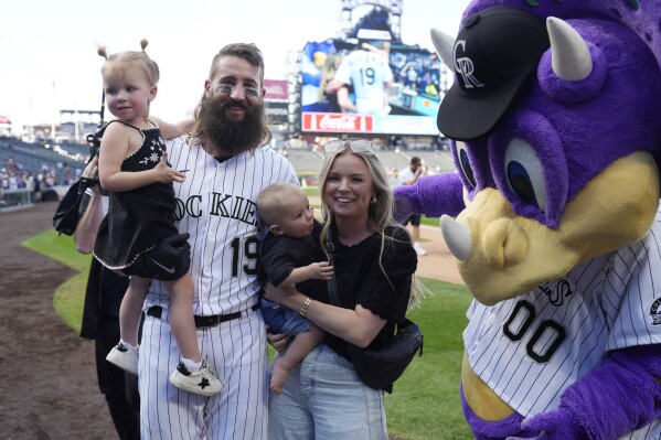 Colorado Rockies designated hitter Charlie Blackmon, second from left, holds his daughter while his wife, Ashley, holds the couple's son as team mascot Dinger greets the family after a baseball game against the Minnesota Twins on Sunday, Oct. 1, 2023, in Denver. (AP Photo/David Zalubowski)