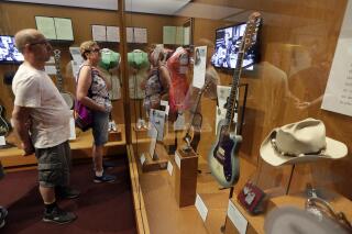 FILE - In this May 25, 2018 photo, visitors to the Country Music Hall of Fame and Museum in Nashville, Tenn. view the the Outlaws & Armadillos exhibit. The NRA has been publicizing plans to auction off firearms at a fundraising dinner at the Country Music Hall of Fame and Museum. But a spokesperson for the museum tells The Associated Press that the April event will not take place there after the AP asked questions about the museum's no firearms policy. (AP Photo/Mark Humphrey, File)