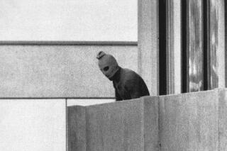 FILE - File Photo from Sept. 5, 1972 shows a member of the Arab Commando group which seized members of the Israeli Olympic Team at their quarters at the Munich Olympic Village appearing with a hood over his face on the balcony of the village building where the commandos held several members of the Israeli team hostage. (AP Photo/Kurt Strumpf, File)