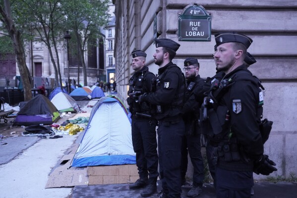 Police officers stand by a makeshift camp during an evacuation operation Tuesday, April 30, 2024 in Paris. Similar operations are carried out by the police authorities on a daily basis in the months leading to the Olympics. (AP Photo/Michel Euler)