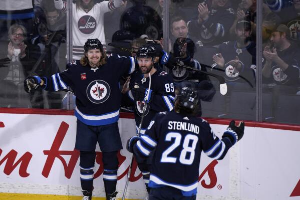 Winnipeg Jets' Axel Jonsson-Fjallby (71) celebrates his goal against the Vancouver Canucks with Sam Gagner (89) and Kevin Stenlund (28) during the second period of an NHL hockey game in Winnipeg, Manitoba, Sunday, Jan. 8, 2023. (Fred Greenslade/The Canadian Press via AP)
