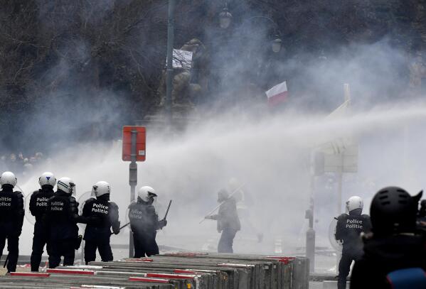 Police set off a water cannon against protestors during a demonstration against COVID-19 measures in Brussels, Sunday, Jan. 23, 2022. Demonstrators gathered in the Belgian capital to protest what they regard as overly extreme measures by the government to fight the COVID-19 pandemic, including a vaccine pass regulating access to certain places and activities and possible compulsory vaccines. (AP Photo/Geert Vanden Wijngaert)