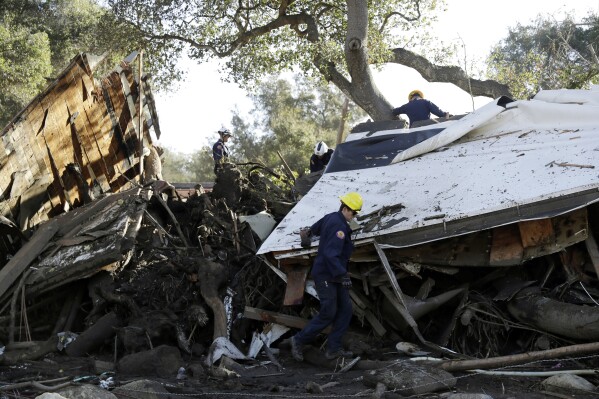 FILE - Search and rescue personnel scan a home in the aftermath of a mudslide, Jan. 13, 2018, in Montecito, Calif. A system of nets intended to catch boulders and other debris during rainstorms in the California hillside community devastated by mudslides five years ago has been removed over a funding dispute. (AP Photo/Marcio Jose Sanchez, File)