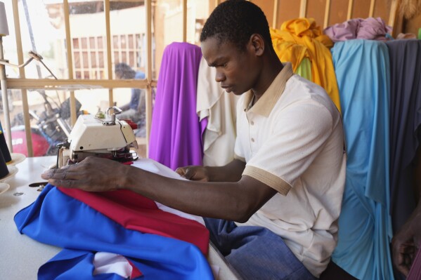 A seamster makes a Russian flag in Niamey, Niger, Thursday, Aug. 24, 2023. Since the coup, Nigeriens have been waving Russian and Wagner flags at protests, fastening them to car windows and selling them in the streets. (AP Photo/Sam Mednick)