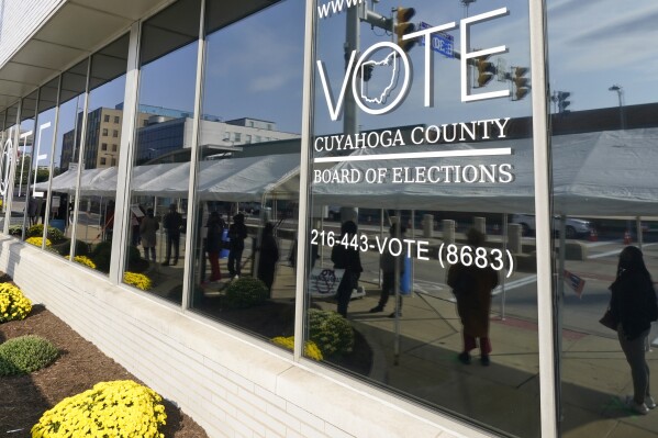 FILE - Voters are reflected in a window as they wait in line to participate in early voting at the Cuyahoga County Board of Elections in Cleveland, Oct. 6, 2020. Voter registration closes Monday, July 10, 2023, in Ohio for a high-stakes Aug. 8 election on whether to make it tougher to amend the state constitution. Early in-person voting starts July 11. (AP Photo/Tony Dejak, File)