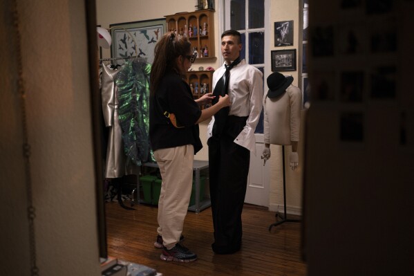 Designer Maria Ponce adjusts Guillermo Barraza's necktie as he tries on outfits for his newscast "La Verdrag", at her studio in Mexico City, Tuesday, Oct. 10, 2023. Through his drag character Amanda, 31-year-old journalist Barraza is the first-ever drag queen to host a news program for Mexican TV. (AP Photo/Aurea Del Rosario)