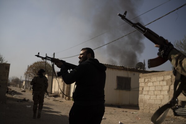 Syrian fighters aims their weapons in direction of suspected looters at a residential complex of former Bashar Assad's military officers at the village of Husseiniyeh, in the outskirts of Damascus, Syria, Sunday, Dec. 15, 2024. (AP Photo/Leo Correa)