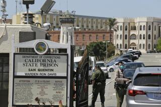 FILE - In this July 9, 2020 file photo a correctional officer checks a car entering the main gate of San Quentin State Prison, in San Quentin, Calif. California is mandating that some correctional officers at state and local facilities and detention centers to get vaccinated unless they qualify for a religious or medical exemption. (AP Photo/Eric Risberg,File)