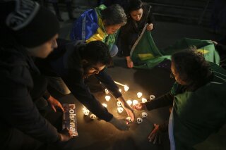 People light candles in support of presidential candidate Jair Bolsonaro, of the National Social Liberal Party, who was stabbed earlier in the day during a campaign event, in Sao Paulo, Brazil, Thursday, Sept. 6, 2018. Officials and his son said Jair Bolsonaro was in stable condition, though the son also said the far-right candidate suffered severe blood loss and arrived to the hospital "almost dead." (AP Photo/Andre Penner)