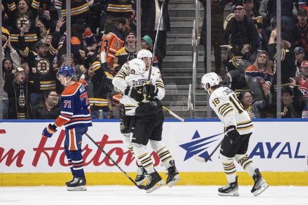 Boston Bruins' Jake DeBrusk (74), Charlie McAvoy (73) and Pavel Zacha (18) celebrate a goal as Edmonton Oilers' Ryan McLeod (71) skates past during overtime an NHL hockey game Wednesday, Feb. 21, 2024, in Edmonton, Alberta. (Jason Franson/The Canadian Press via 麻豆传媒app)