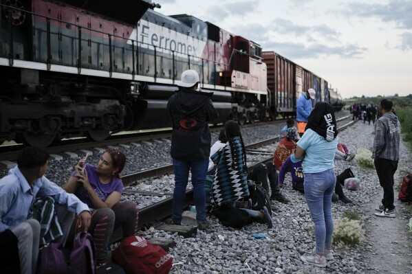 Migrants watch a train go past as they wait along the train tracks hoping to board a freight train heading north, in Huehuetoca, Mexico, Sept. 19, 2023. Ferromex, Mexico's largest railroad company announced that it was suspending operations of its cargo trains due to the massive number of migrants that are illegally hitching a ride on its trains moving north towards the U.S. border. (AP Photo/Eduardo Verdugo)