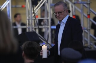 Australian Prime Minister Anthony Albanese carries a candle during a candlelight vigil at Sydney's Bondi Beach to remember victims of a knife attack at a nearby shopping mall, Australia, Sunday, April 21, 2024. An assailant was shot and killed by a police officer on April 13, after he stabbed six people to death and wounded more than a dozen others in an attack that police believe targeted women. (AP Photo/Mark Baker)
