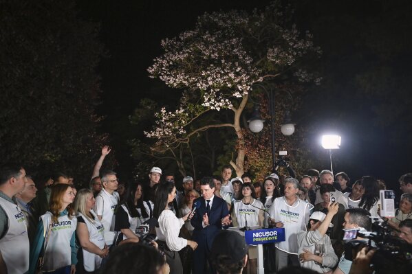 Presidential candidate Nicusor Dan speaks to media, surrounded by supporters, after polls closed in the first round of the country's presidential election redo in Bucharest, Romania, Sunday, May 4, 2025. (AP Photo/Eduard Vinatoru)