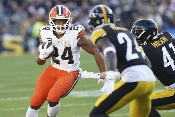 Cleveland Browns running back Nick Chubb (24) carries as Pittsburgh Steelers cornerback Joey Porter Jr. (24) and linebacker Payton Wilson (41) defend in the second half of an NFL football game in Pittsburgh, Sunday, Dec. 8, 2024. (AP Photo/Matt Freed, File)