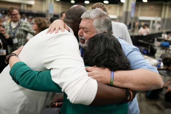 FILE - David Meredith, middle, hugs fellow observers after an approval vote at the United Methodist Church General Conference Wednesday, May 1, 2024, in Charlotte, N.C. When the United Methodist Church removed anti-LGBTQ language from its official rules in recent days, it marked the end of a half-century of debates over LGBTQ inclusion in mainline Protestant denominations. The moves sparked joy from progressive delegates, but the UMC faces many of the same challenges as Lutheran, Presbyterian and Episcopal denominations that took similar routes, from schisms to friction with international churches to the long-term aging and shrinking of their memberships. (AP Photo/Chris Carlson, File)
