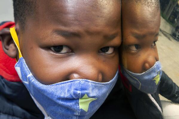FILE - A child wears a face mask to protect against coronavirus at a Johannesburg Mall, in Johannesburg, Monday, Dec. 20, 2021. With declining cases of COVID-19, South Africa's president has announced that it is no longer mandatory to wear masks outdoors and vaccinated travelers entering the country are no longer required to produce negative PCR tests.(AP Photo/Denis Farrell, File)