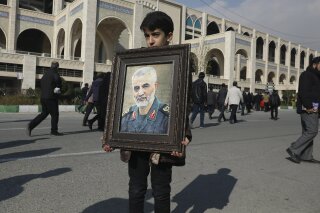 A boy carries a portrait of Iranian Revolutionary Guard Gen. Qassem Soleimani, who was killed in the U.S. airstrike in Iraq, prior to the Friday prayers in Tehran, Iran, Friday Jan. 3, 2020. Iran has vowed "harsh retaliation" for the U.S. airstrike near Baghdad's airport that killed Tehran's top general and the architect of its interventions across the Middle East, as tensions soared in the wake of the targeted killing. (AP Photo/Vahid Salemi)
