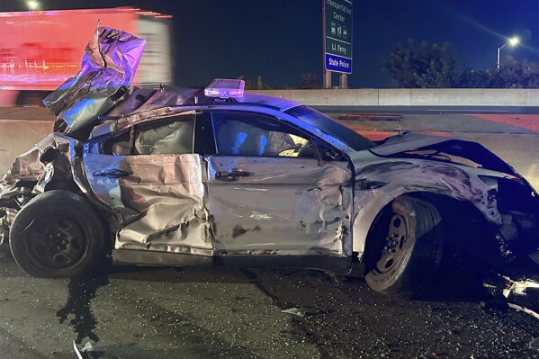 This image released by the Connecticut State Police, Tuesday, July 18, 2023, shows one of of two state police cruisers damaged when human waste, leaking from a tractor trailer, turned Interstate 95 in Bridgeport, Conn., into a virtual skating rink, causing multiple crashes, Monday night, July 17, 2023. State police charged the driver with reckless driving, reckless endangerment and failing to secure a load. (Connecticut State Police via AP)