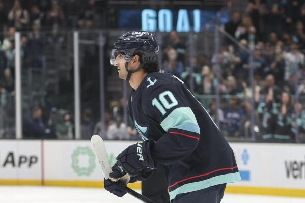 Seattle Kraken forward Matty Beniers (10) skates to the bench after scoring a goal during the second period of the team's preseason NHL hockey game against the Vancouver Canucks on Saturday, Oct. 1, 2022, in Seattle. (AP Photo/Jason Redmond)