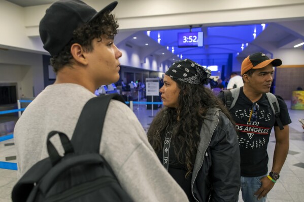 Cuban migrants Yenny Leyva Bornot, center, her husband, Jose Enrique Cespedes, right, and son, John Angel Cespedes, stand together in the El Paso International Airport in El Paso, Texas, early Friday, Aug. 9, 2024. (AP Photo/Andres Leighton)