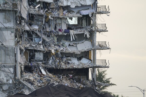FILE - A giant tarp, bottom, covers a section of rubble at the Champlain Towers South condo building, July 4, 2021, in Surfside, Fla. The probe into the 2021 collapse of the beachfront condominium building that killed 98 people in South Florida should be completed by the fourth anniversary of the disaster, federal officials said Thursday, Sept. 7, 2023. (AP Photo/Lynne Sladky, File)