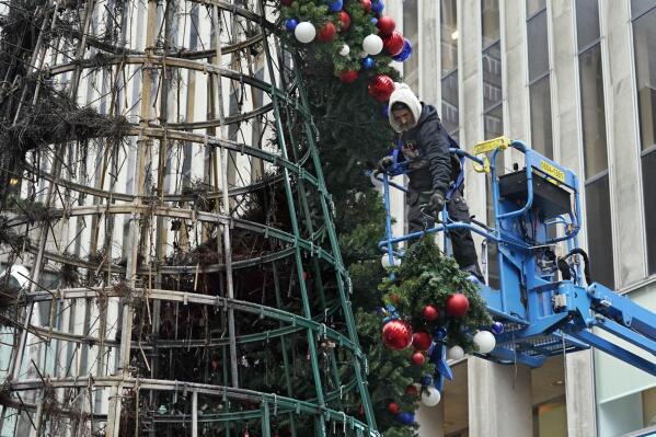 A worker disassembles a Christmas tree outside Fox News headquarters, in New York, Wednesday, Dec. 8, 2021. Police say a man is facing charges including arson for setting fire to a 50-foot Christmas tree in front of Fox News headquarters in midtown Manhattan. The tree outside of the News Corp. building that houses Fox News, The Wall Street Journal and the New York Post caught fire early Wednesday. (AP Photo/Richard Drew)