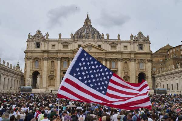 A flag from the United States waves in the crowd as Pope Leo XIV appears at the central balcony of St. Peter's Basilica for his first Sunday blessing after his election, in St. Peter's Square at the Vatican, Sunday, May 11, 2025.(AP Photo/Bernat Armangue)
