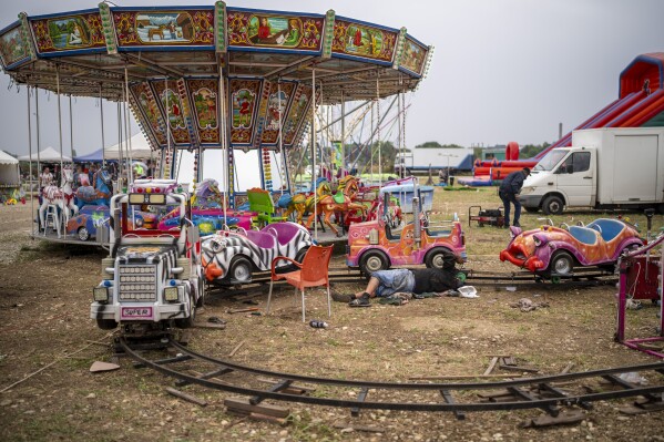 A man repairs a carousel at a fair in Hagioaica, Romania, Saturday, Sept. 16, 2023. For many families in poorer areas of the country, Romania's autumn fairs, like the Titu Fair, are one of the very few still affordable entertainment events of the year. (AP Photo/Vadim Ghirda)