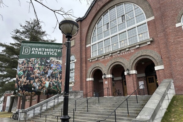 FILE A Dartmouth Athletics banner hangs outside Alumni Gymnasium on the Dartmouth University campus in Hanover, N.H., March 5, 2024. Efforts to unionize college athletes will continue, advocates said Friday, May 24, 2024, even with the NCAA’s agreement this week to allow players to be paid from a limited revenue-sharing pool. (AP Photo/Jimmy Golen, File)