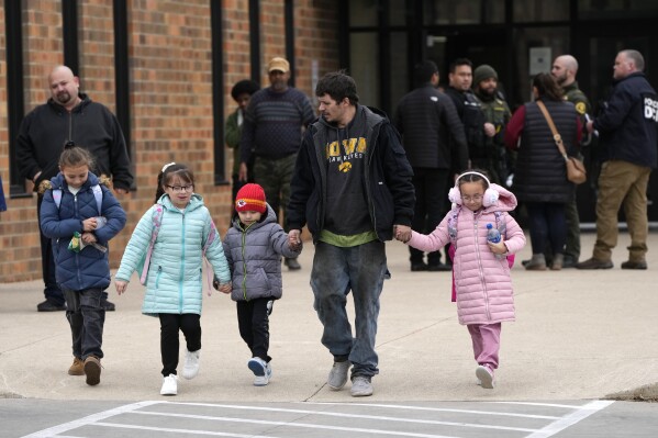 A man and his children leave the McCreary Community Building after gathering following a shooting at Perry High School, Thursday, Jan. 4, 2024, in Perry, Iowa. (AP Photo/Charlie Neibergall)