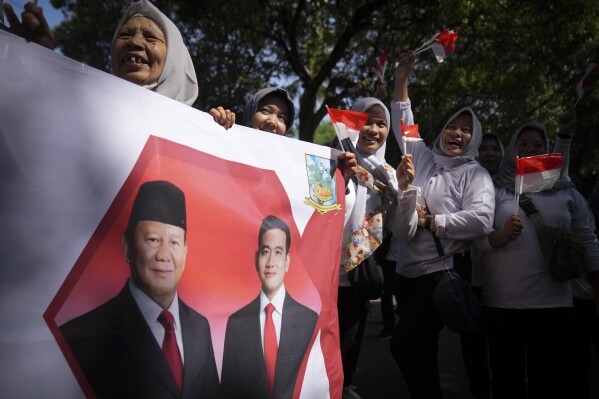 Indonesian supporters waves Indonesia flag and hold banner show Indonesian president-elect Prabowo Subianto, left, and vice president-elect Gibran Rakabuming Raka, who is also the eldest son of outgoing President Joko Widodo in Jakarta, Indonesia, Sunday, Oct. 20, 2024. (AP Photo/Dita Alangkara)