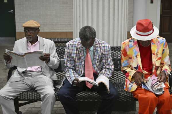 People look over racing programs at Churchill Downs before the 151st running of the Kentucky Oaks horse race, Friday, May 2, 2025, in Louisville, Ky. (AP Photo/Jon Cherry)