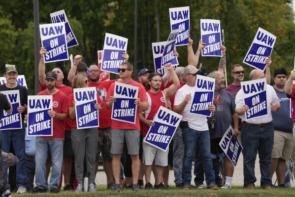 FILE - United Auto Workers members hold picket signs near a General Motors assembly plant in Delta Township, Mich., Sept. 29, 2023. About 46,000 United Auto Workers at GM are expected to wrap up voting on a tentative contract agreement in a close race that will decide the fate of the deal that ended a six-week strike. The union is expected to announce GM results Thursday evening. (AP Photo/Paul Sancya, File)