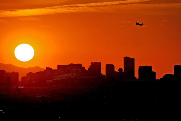 FILE - A jet takes flight from Sky Harbor International Airport as the sun sets over Phoenix, July 12, 2023. Homeless people are among the people most likely to die in the extreme heat in metro Phoenix. (AP Photo/Matt York, File)